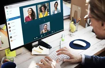 A man at a desk on a video call with four other people on screen