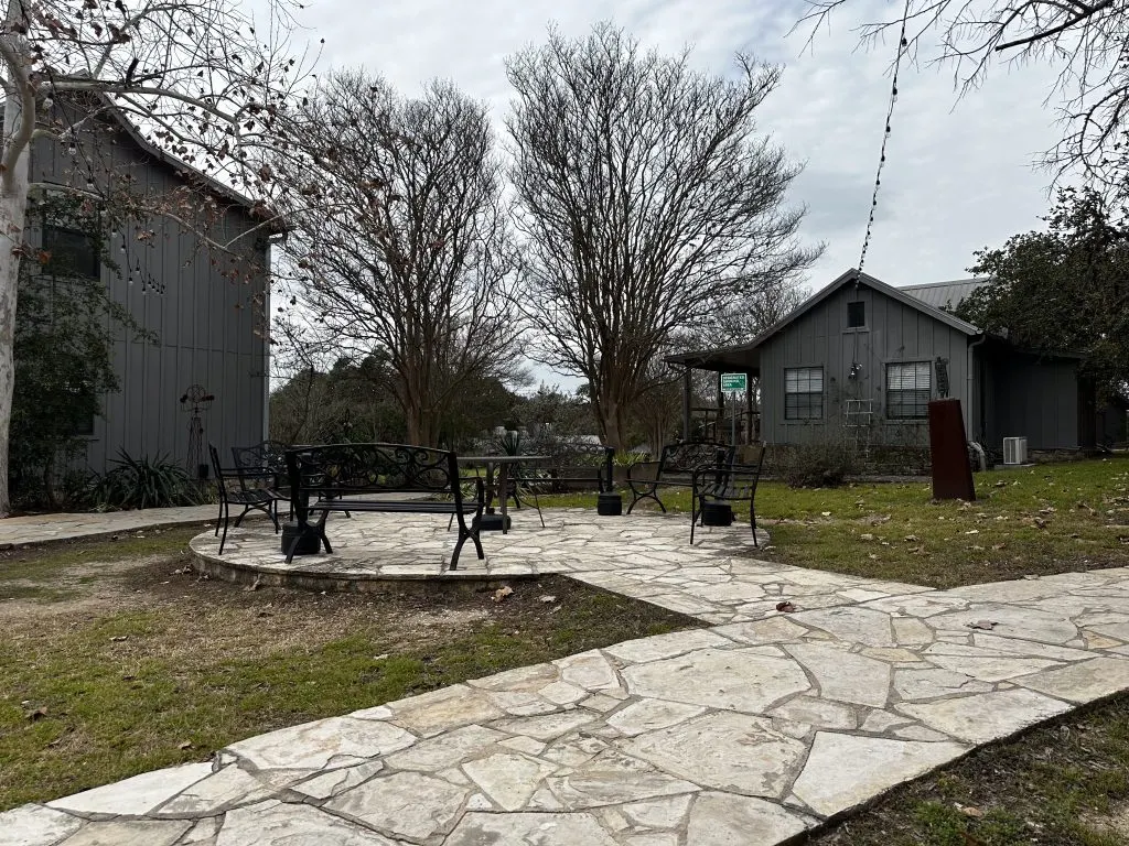Stone patio under live oaks with wicker seating at Nova Recovery Center’s Texas Hill Country rehab campus.