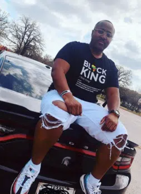 Man wearing a “Black King” t-shirt sitting on a Dodge Challenger, symbolizing strength and resilience in recovery from drug addiction.