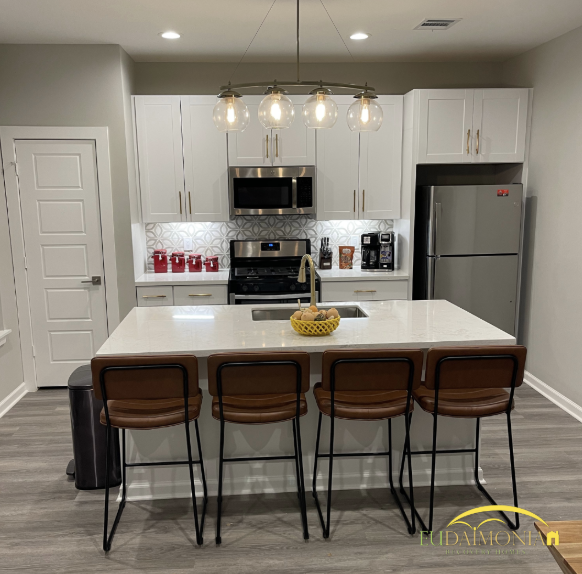 Fully equipped kitchen with island seating, stainless appliances, and pendant lights in Houston sober living.
