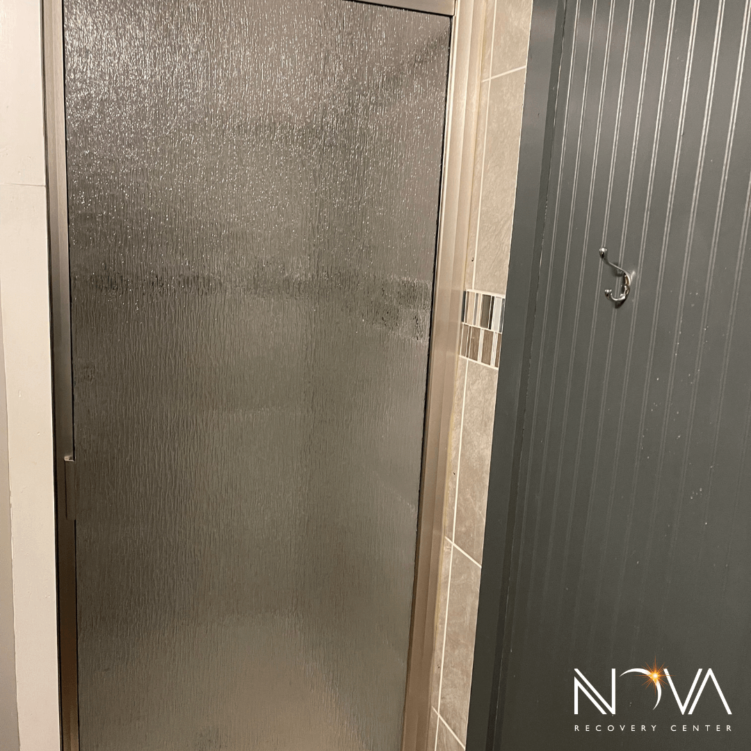 Walk‑in shower with frosted glass door and tiled surround at the Austin rehab facility.