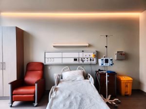 a hospital room with a bed and a chair -- Photo by Max Tcvetkov on Unsplash