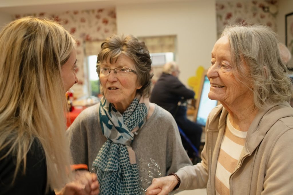 Three women talking and smiling in a room -- Photo by Age Cymru on Unsplash