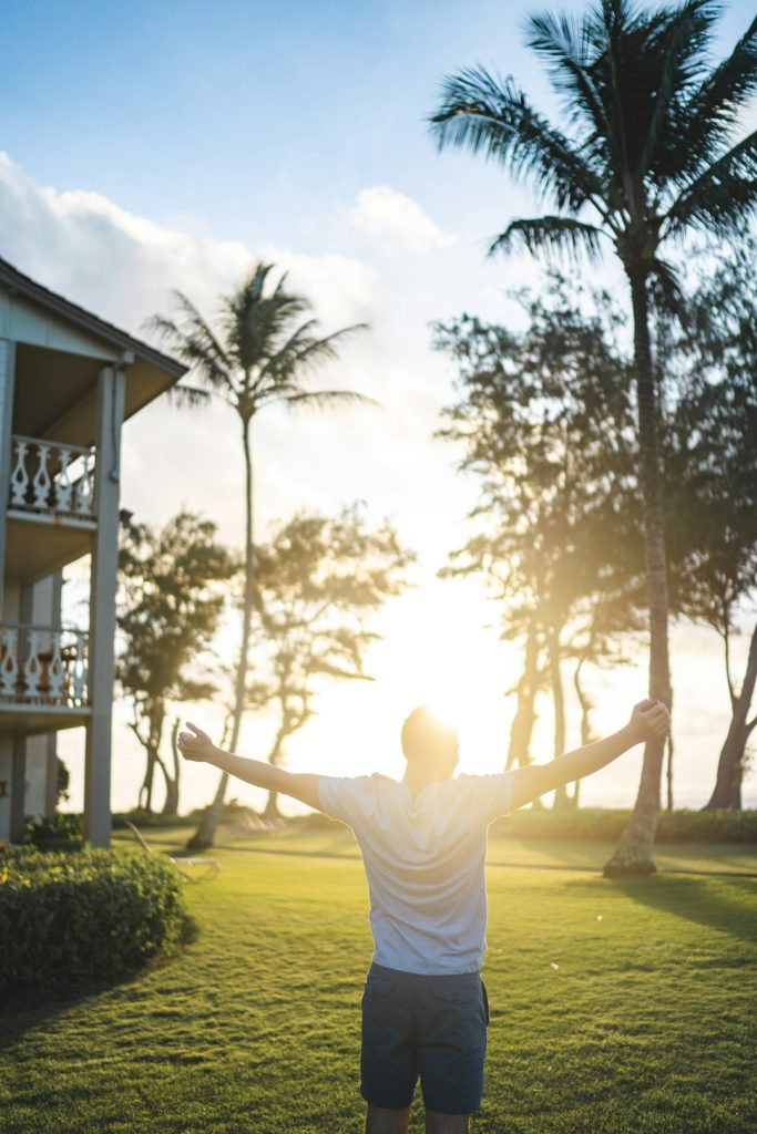 man in white shirt standing while raising hands near house -- Photo by Belle Collective on Unsplash