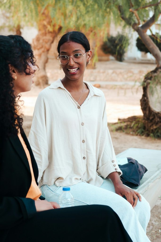 Two women talking while sitting on a bench outdoors. -- Photo by Amari Shutters on Unsplash