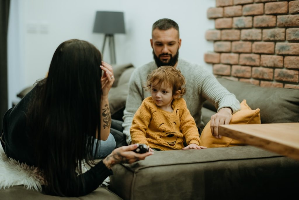 a man sitting on a couch next to a little girl -- Photo by Tamara Govedarovic on Unsplash