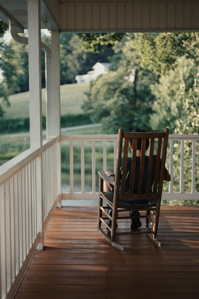 a person sitting on a rocking chair on a porch -- Photo by Tolga Ahmetler on Unsplash