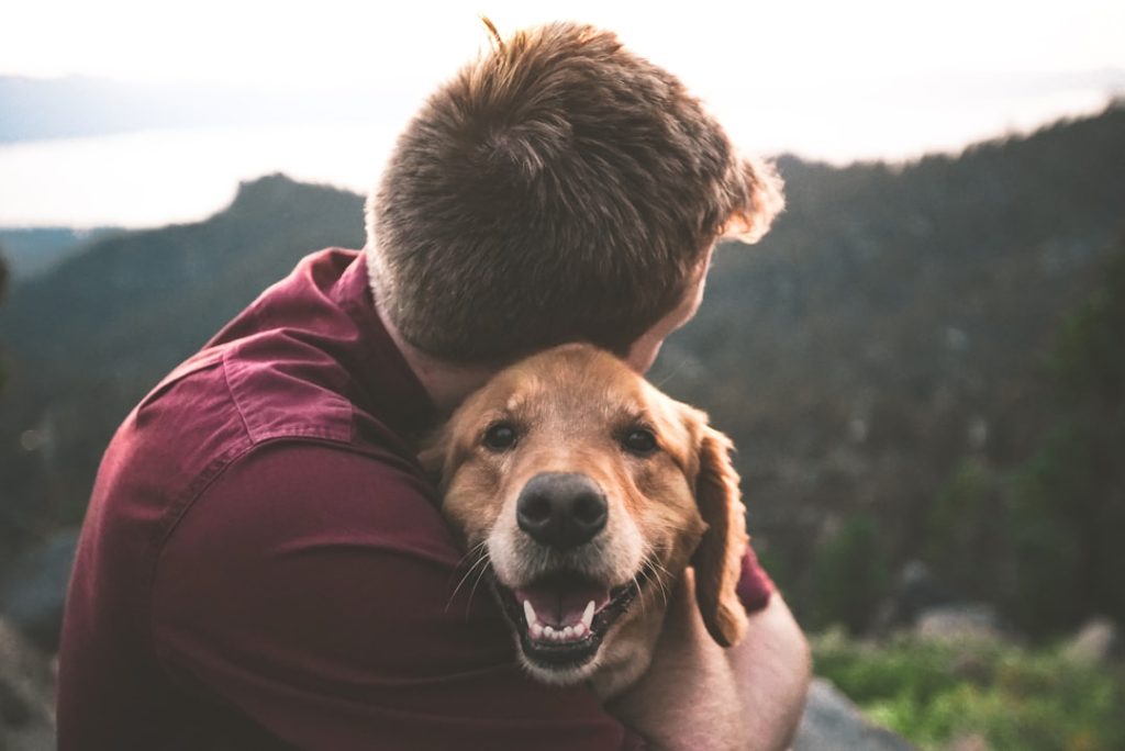 photo of man hugging tan dog -- Photo by Eric Ward on Unsplash